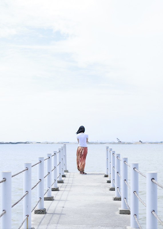 Woman in a pier looking at the sea